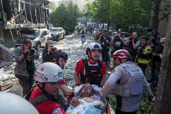 Os voluntários da Cruz Vermelha evacuam uma mulher ferida.